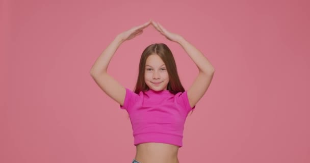 Ragazza divertente bambino rendendo casa gesto tetto sopra la testa muovendosi su sfondo studio rosa. Assicurazione sulla vita, concetto di protezione — Video Stock