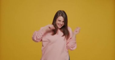 Dans eden genç kız eğleniyor, müzik dinliyor, gülümsüyor, kutlama yapıyor sarı arka planda zafer dansı yapıyor. 