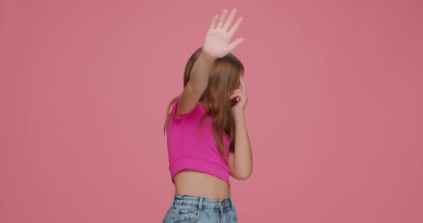 Anak perempuan yang ketakutan menutup mata dengan tangan dan melakukan gerakan berhenti dengan ekspresi ketakutan di latar belakang studio merah muda — Stok Video