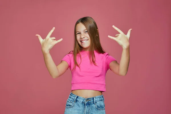 Cool rossz gyerek lány Tomboy show rock, heavy metal gesztus kézzel, szórakozás rózsaszín stúdió háttér — Stock Fotó