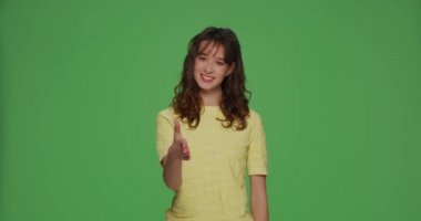 Gülümseyen genç kız el sıkışmak için elini uzatıyor. Yeşil arka planda iş ortaklığı teklif ediyor.