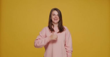 Komik genç kız iyi bir jest yapıyor iyi bir servis öneriyor, sarı arka planda ürün reklamı yapıyor. Olumlu geri bildirim