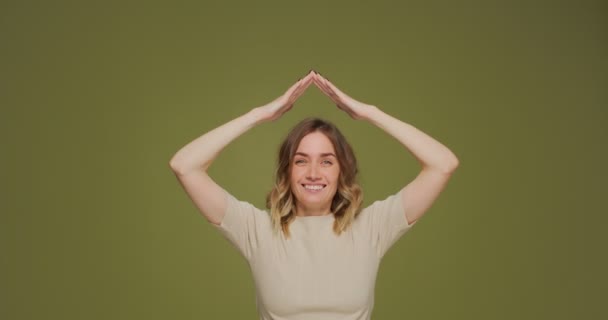 Mujer joven feliz haciendo gesto de techo de la casa sobre la cabeza sonriendo, soñando con la compra de una casa, hipoteca favorable — Vídeo de stock