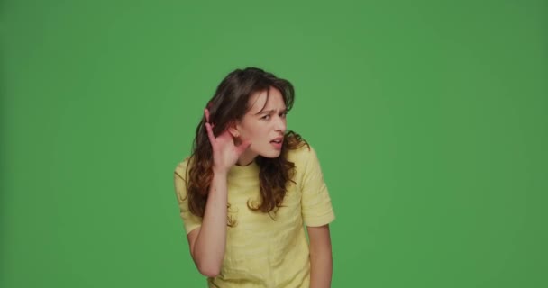 Проблемы со слухом. Молодая девушка поднесла руки к ушам, пыталась слушать тихие сплетни, узнавала информацию на зеленом фоне — стоковое видео