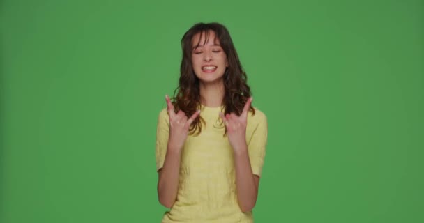 Glimlachend meisje rocker show cool rock-n-roll gebaar symbool door de handen, maken rock teken op chromakey groene studio achtergrond — Stockvideo