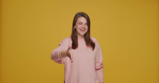 Smilende, ung kvinne som strekker ut hånden for håndtrykk tilbyr samarbeid ved å se på kamera. Introduksjonsmodell – stockvideo
