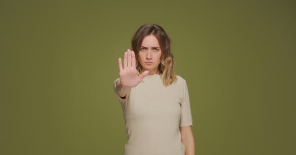 Une jeune femme sérieuse montre un geste d'arrêt des paumes à la caméra, protestant contre la discrimination de genre, demandant de garder ses distances — Video