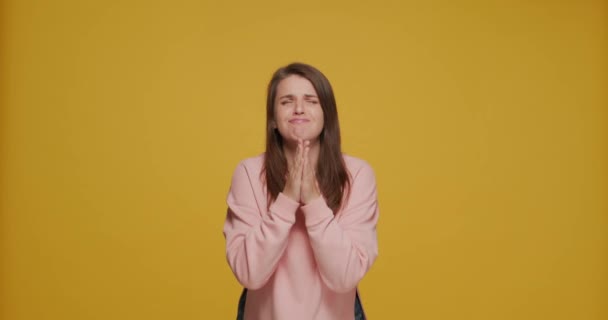 Emocionada chica joven emocional suplicando pidiendo algo con las manos cerradas diciendo por favor en el fondo amarillo — Vídeos de Stock