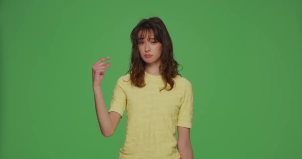 Upset young girl look at hand showing with pity little size gesture, shrug and sigh on chromakey green studio background — Vídeo de Stock