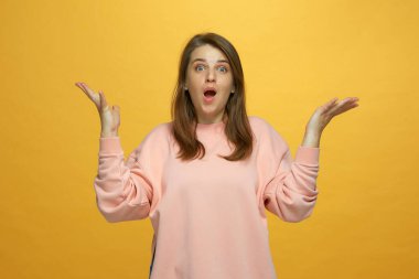 Şok olmuş genç bir kız ağzı açık sarı arka planda elleri açık geziyor. Büyük indirim kavramı