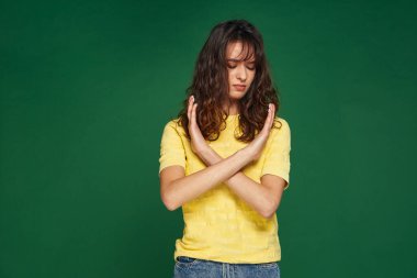 Ciddi genç kız hayır diyerek ellerini çapraz yaptı, dur uyarısı, iletişimi kesme, yeşil arka plana bakma
