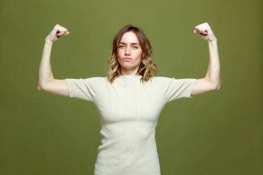 Kendine güveni tam genç bir kadın kas gücü ve bağımsızlık gösteriyor, kollarını kaldırıyor. Kız gücü, feminizm kavramı
