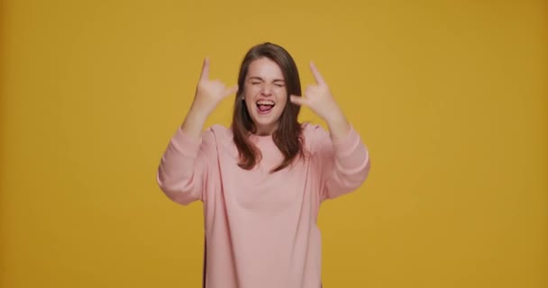 Galen rolig överlycklig ung flicka visa rock-n-roll gest, ha kul, njuta av rock energisk musik på gul bakgrund — Stockvideo