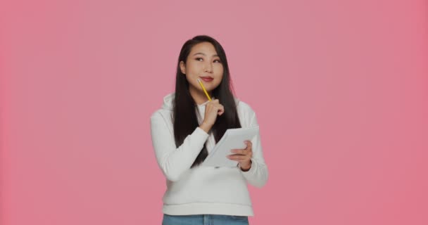 Smiling pensive asian young girl make notes in notepad, writing ideas, feel ecstatic find out decision, solving task — Vídeo de Stock