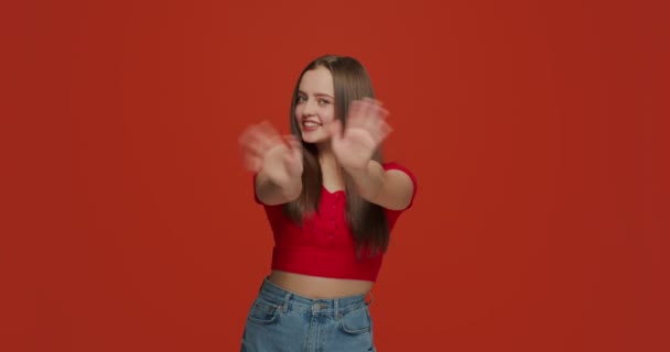 Friendly young girl smiling blogger waving hands make greeting gesture, welcoming, communicate on orange background — Vídeo de Stock