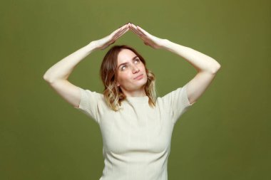 Genç bir kadın el hareketleriyle çatı jesti, güvenlik sembolü, koruma, yeni ev, satın alma hayali