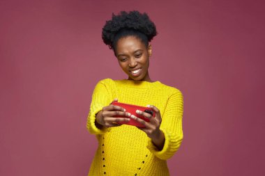 Happy african american young woman enjoy playing online game using modern mobile phone apps toothy smiling