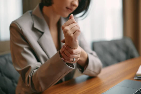 Female suffer from wrist pain massage hand, work in office, close-up. Carpal tunnel syndrome, long-term use of keyboard