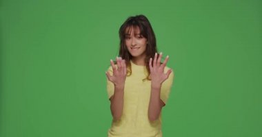 Modern young girl calling with hands, making beckoning gesture, inviting to come on chromakey green background