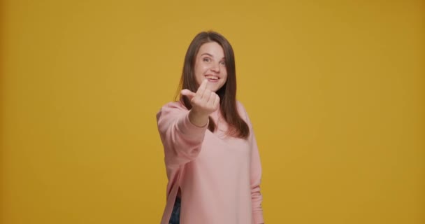 Happy young girl make beckoning hands gesture, asking come here, inviting, welcoming, smiling on yellow background — Stok video