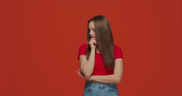 Pensive young modern girl solving problem, planning, decide cognitive task, pondering idea on orange studio background — Stock Video