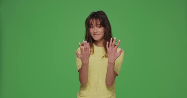 Modern young girl calling with hands, making beckoning gesture, inviting to come on chromakey green background — стоковое видео