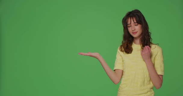 Product advertisement. Young girl presenting copy space on palm, showing empty place for sale offer on green background — Stok video