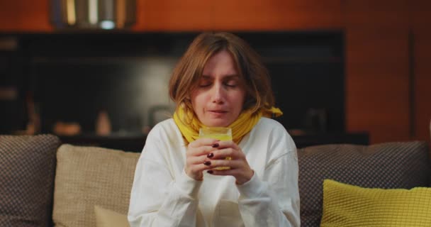 Enferma mujer joven sosteniendo medicina vidrio beber remedio sentado en el sofá en casa, enferma enferma enferma hembra en licencia por enfermedad — Vídeo de stock