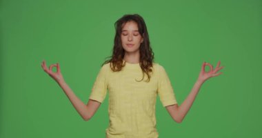 Calm young girl breathing making mudra om hands eyes closed, relive negative emotions or stress, breathe fresh air