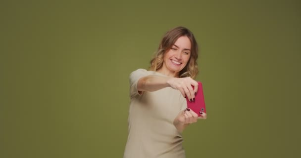 Excited funny young woman playing video game using smart phone application having fun, grimacing on green background — Stockvideo