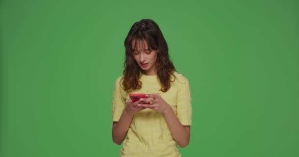 Досить щаслива молода дівчина спілкується, використовуючи додатки соціальних мереж на мобільному телефоні на зеленому фоні хромосоми. оголошення програми знайомств — стокове відео