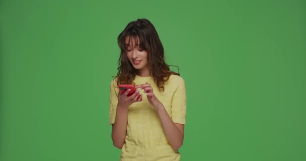 Happy young girl hold phone reading good news in social media watching funny video content on chromakey green background — 图库视频影像