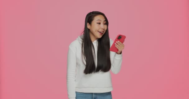 젊은 아시아인 소녀가 좋은 소식을 읽고 온라인 쇼핑 프로 모 코드를 따거나 사회 연결망에서 상을 타는 것을 보고는 깜짝 놀랐습니다. — 비디오
