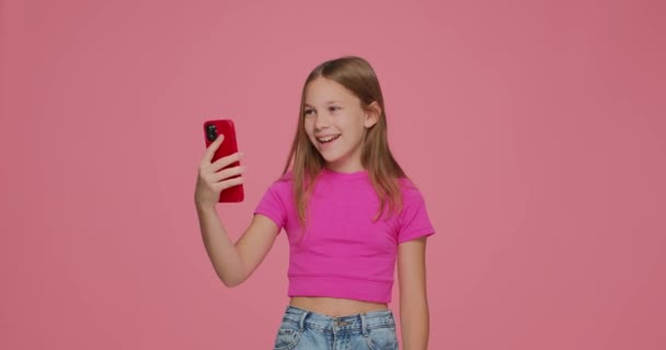 Sorpreso carino bambino ragazza tenere il telefono si sentono entusiasti di vincere gioco online, social network giveaway su sfondo rosa studio — Video Stock