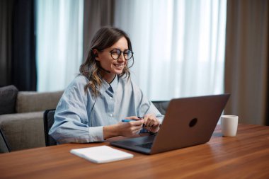 Kulaklıklı mutlu genç kız danışman dizüstü bilgisayarda webinar izlemekten, müşterilerle ya da ortaklarla video görüşmesi yapmaktan zevk alır.