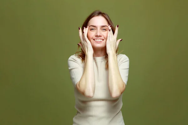 Sonriente joven de 30 años toque femenino piel suave y saludable sobre fondo de oliva. Belleza mujer natural, cosméticos para el cuidado de la piel ad — Foto de Stock