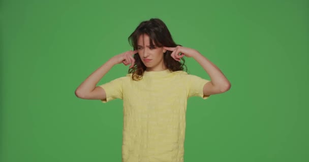 Stubborn irritated young girl sticking plug fingers in ears not listening, refuse hear on chromakey green background — Stock Video