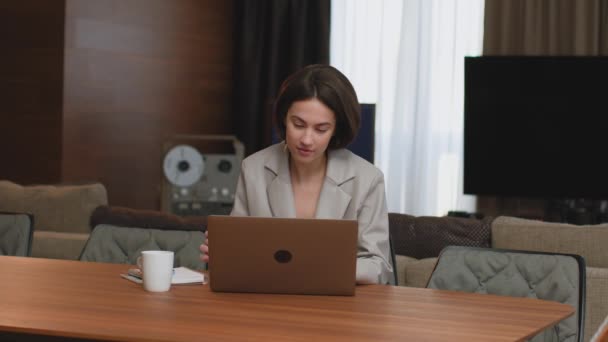 Jonge vrouwelijke zakenvrouw ondernemer werkt online, typt e-mail op laptop aan het bureau, het drinken van thee in huis kantoor — Stockvideo