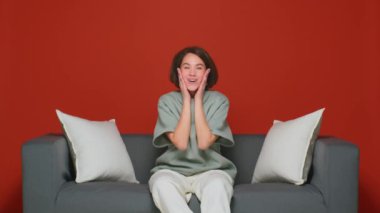 Mutluluğun belirgin bir duygusudur. Vay canına. Kanepede TV dizisi ya da film izlemek. Kırmızı arka planda genç bir kız.