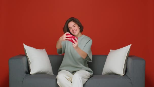 Ein fröhliches, fröhliches Mädchen zu Hause spielt mobile Online-Spiele auf dem Smartphone. Freizeit auf der Couch. Wochenende. — Stockvideo