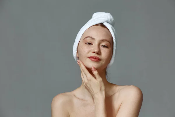 Mooi jong meisje in handdoek met naakte schouders, aanraking schone gezonde huid, tevreden met huidverzorging gezicht — Stockfoto