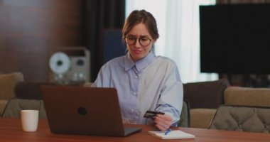 Bilgisayarda çalışan iş kadını banka kredi kartını elinde tutuyor ve vergilerini ödüyor. E-ticaret, e-ticaret konsepti