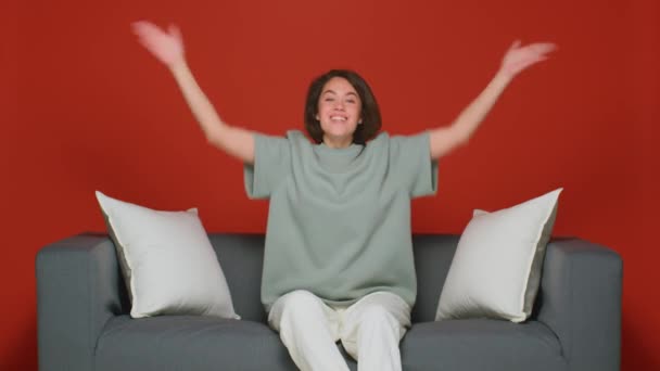 Una donna è seduta sul divano a casa a guardare la TV. Wow emozione, gioia e sorpresa. — Video Stock