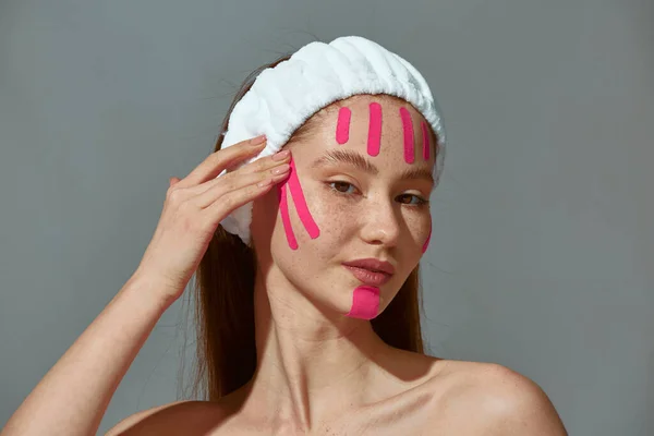 Gezichtsopname. Jong meisje plakken anti rimpels patches strips op wangen voor het aanscherpen van de huid. Verjongingsbehandeling — Stockfoto