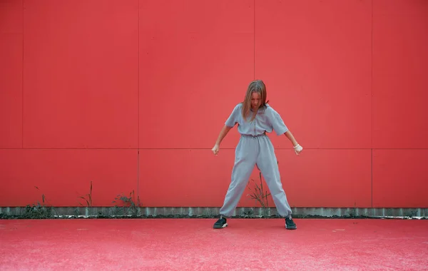 Stílusos kislány pózol a szabadban a vörös fal hátterében. Fiatal női táncos készüljön fel a fellépésre. Fénymásolási hely — Stock Fotó