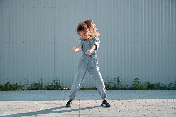 Dansçı kız, kentin arka planında dalgalanan saçlarla mutlu mesut hareket ediyor. Enerjik neşeli genç bayan dansçı. — Stok fotoğraf