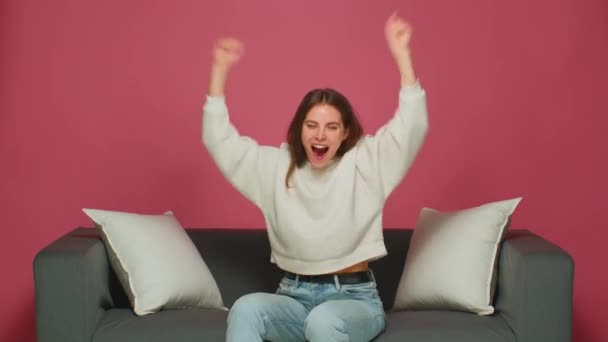 Boldog kilépett fiatal lány fan örülni siker győzelem, úgy érzi, eufórikus, kiabálás, felemeli a kezét, ül a kanapén — Stock videók