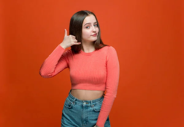 Gyönyörű modern fiatal lány bemutató hívjon gesztus ujjaival, javasoljuk a kommunikációt narancs stúdió háttér — Stock Fotó