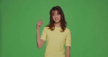 Gülümseyen genç kız küçük boy jest yap, biraz daha indirim ya da krom anahtar arka planda maaş artışı için yalvar