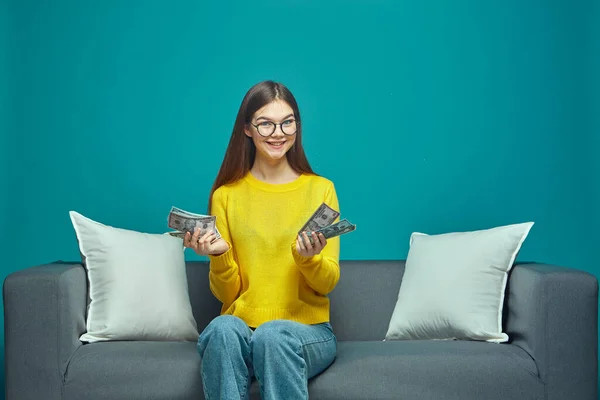 Šťastná mladá dívka počítat peníze, držení v ruce těší finanční odměnu, plat, sedí na gauči — Stock fotografie